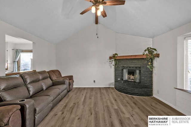 living room with vaulted ceiling with beams, light hardwood / wood-style floors, ceiling fan, and a brick fireplace