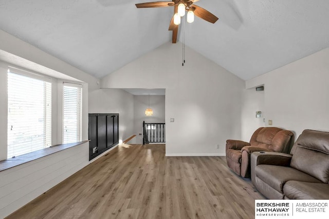 living room featuring vaulted ceiling with beams, light wood-type flooring, and ceiling fan