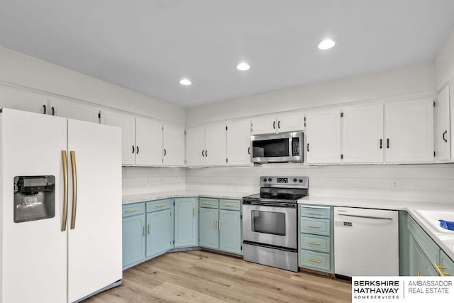 kitchen with white cabinets, appliances with stainless steel finishes, light wood-type flooring, and backsplash