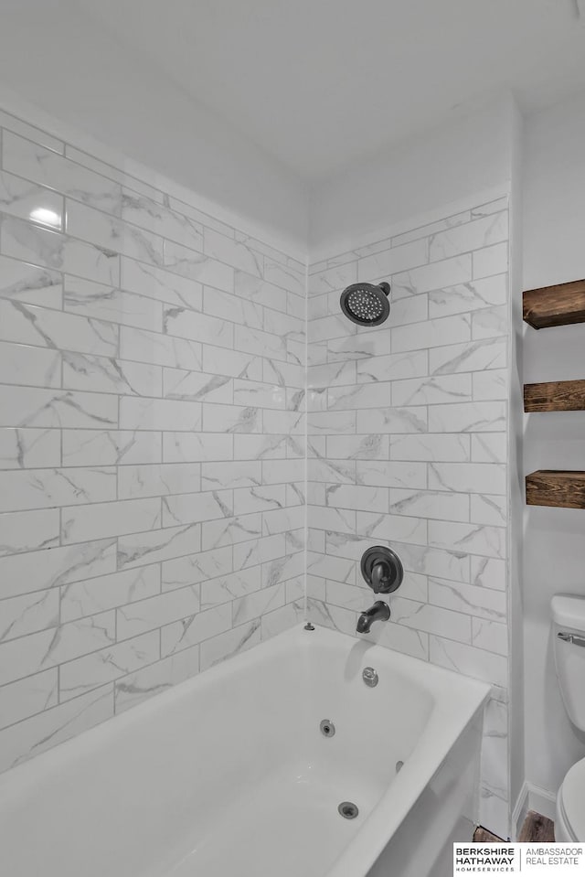 bathroom featuring tiled shower / bath combo and toilet