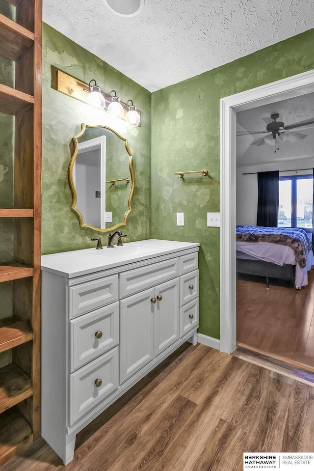 bathroom with vanity, a textured ceiling, hardwood / wood-style flooring, and ceiling fan