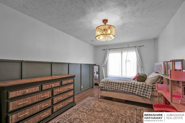 bedroom featuring wood-type flooring, a textured ceiling, and an inviting chandelier