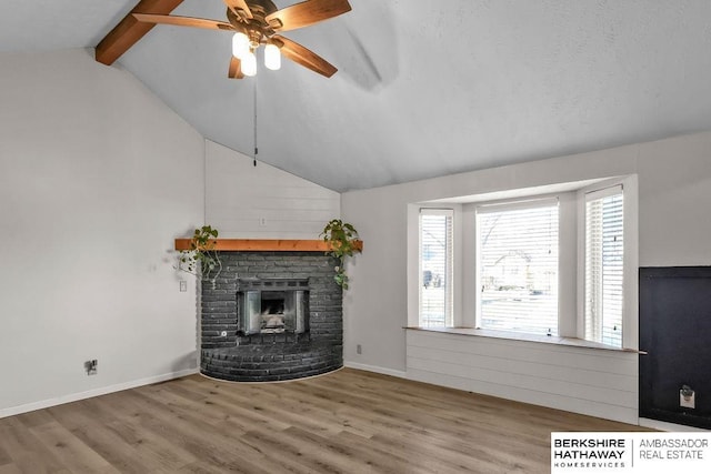 unfurnished living room featuring lofted ceiling with beams, ceiling fan, a fireplace, and light hardwood / wood-style floors