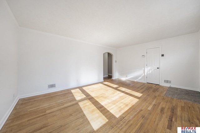 spare room featuring wood-type flooring and crown molding