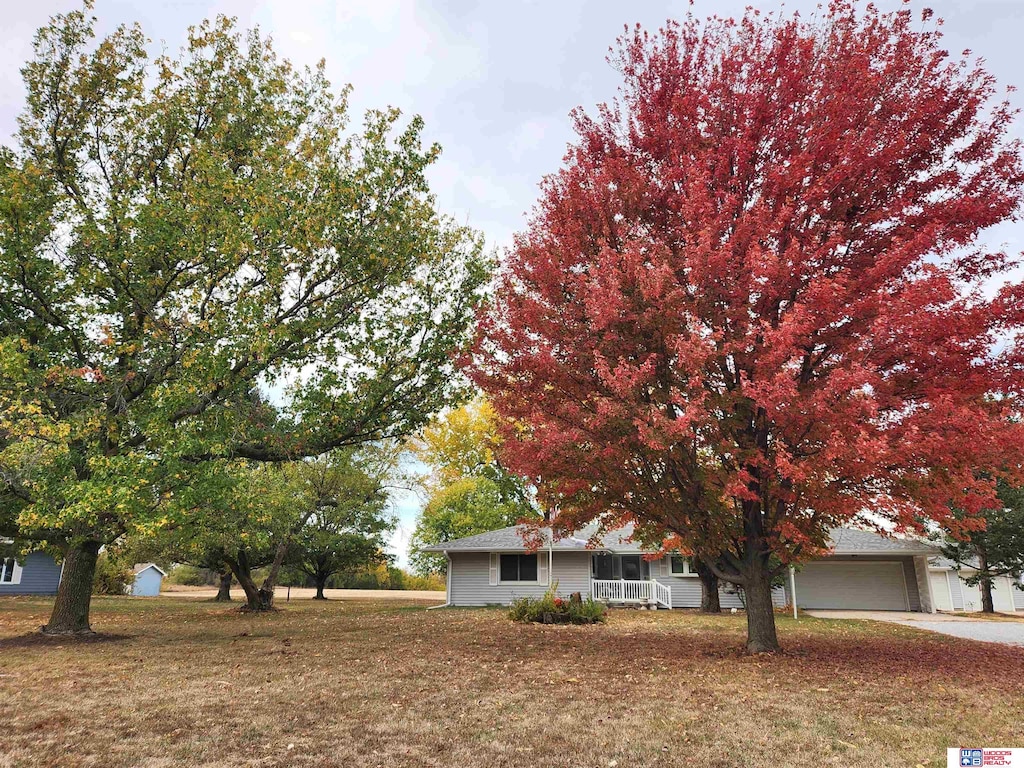 view of front of home featuring covered porch, a front yard, and a garage