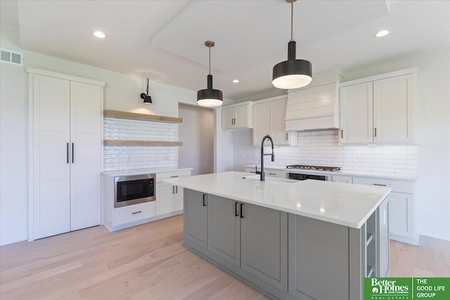 kitchen with sink, white cabinets, and an island with sink