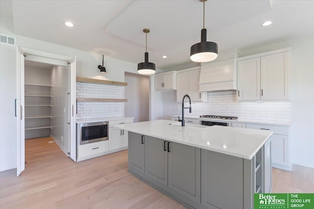 kitchen featuring white cabinetry, a kitchen island with sink, and sink