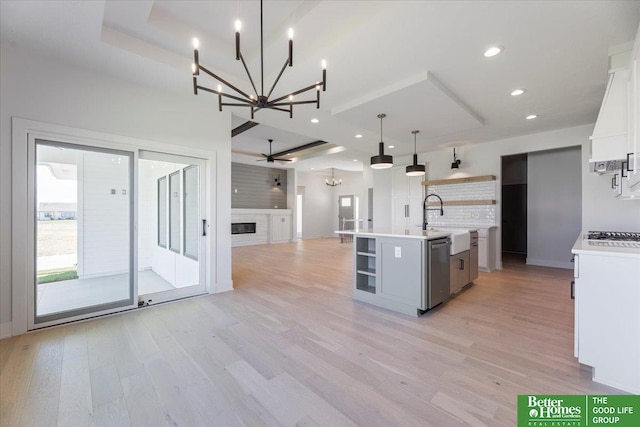 kitchen featuring stainless steel dishwasher, ceiling fan, pendant lighting, white cabinets, and an island with sink