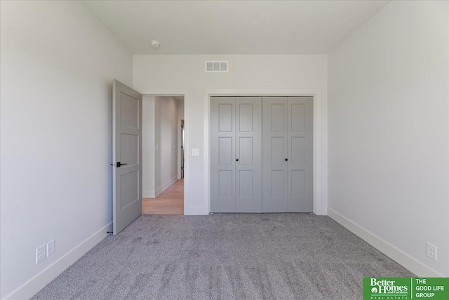 unfurnished bedroom with a closet and light colored carpet