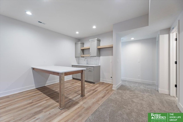 interior space with gray cabinetry, decorative backsplash, light hardwood / wood-style floors, and sink