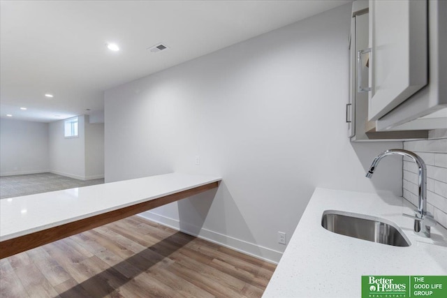 interior space featuring light stone countertops, sink, and light hardwood / wood-style flooring