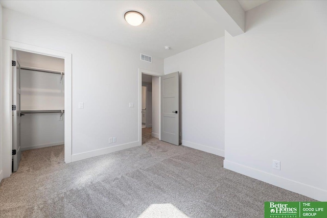 unfurnished bedroom featuring light carpet, a walk in closet, and a closet