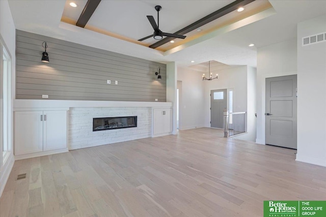 unfurnished living room featuring a raised ceiling, light wood-type flooring, and a fireplace