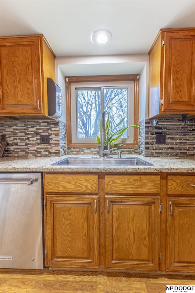 kitchen featuring light stone countertops, decorative backsplash, sink, and stainless steel dishwasher