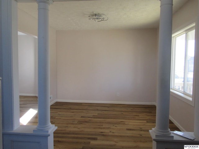 empty room featuring dark hardwood / wood-style flooring and ornate columns