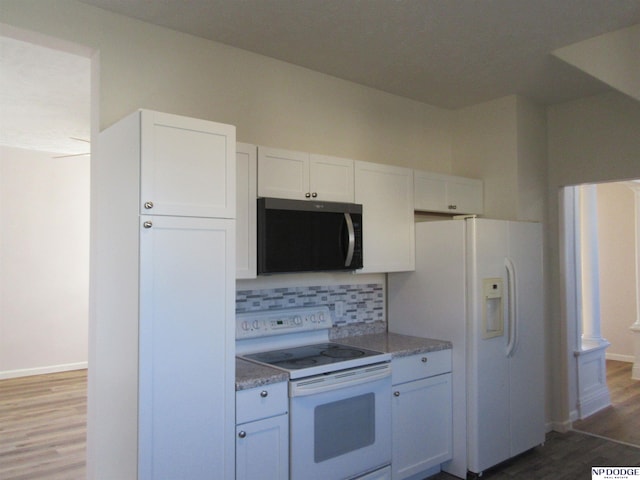 kitchen featuring white appliances, dark wood-type flooring, decorative backsplash, stone countertops, and white cabinetry