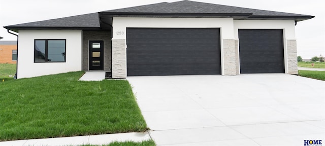 prairie-style house featuring a garage and a front lawn