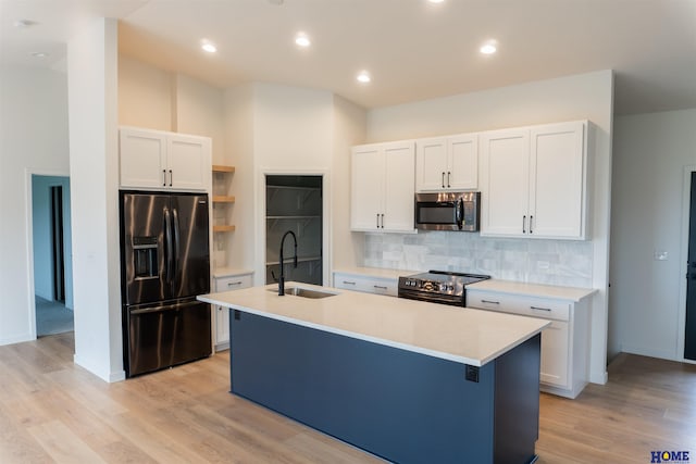 kitchen with appliances with stainless steel finishes, sink, white cabinetry, and an island with sink