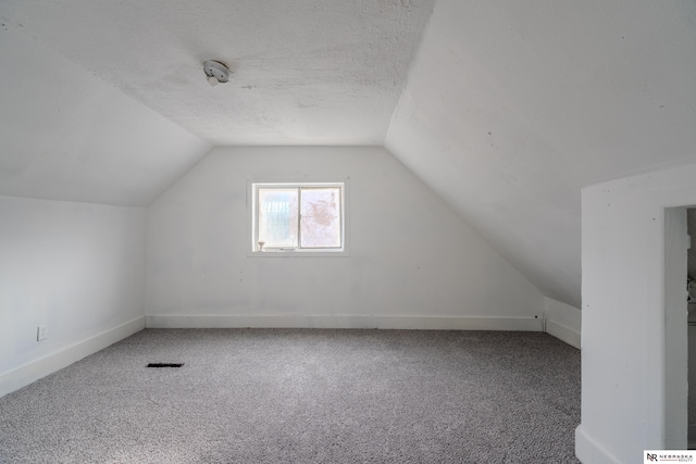 bonus room featuring lofted ceiling, carpet, and a textured ceiling