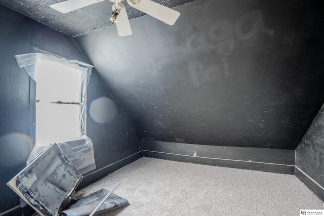 interior space with ceiling fan, carpet floors, and vaulted ceiling