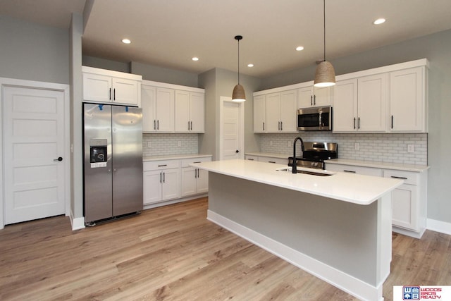 kitchen with pendant lighting, sink, appliances with stainless steel finishes, white cabinetry, and tasteful backsplash