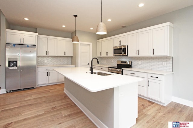 kitchen featuring appliances with stainless steel finishes, sink, hanging light fixtures, and white cabinets