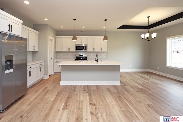 kitchen with stainless steel appliances, white cabinetry, and pendant lighting