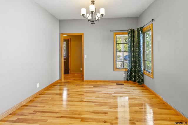 unfurnished room featuring light hardwood / wood-style floors and an inviting chandelier