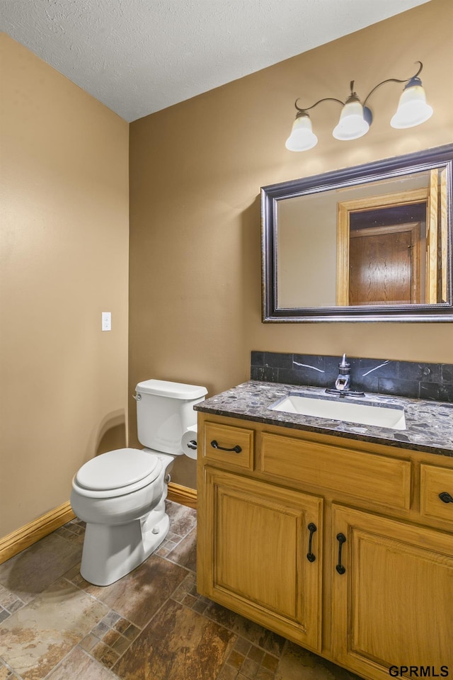 bathroom featuring vanity, toilet, and a textured ceiling