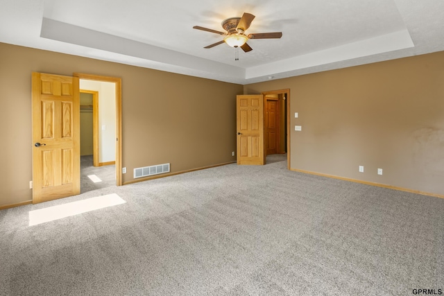 spare room featuring light carpet, a raised ceiling, and ceiling fan