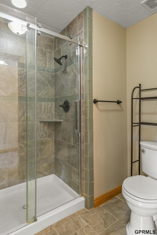 bathroom with tile patterned floors, a textured ceiling, toilet, and walk in shower