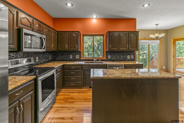 kitchen with appliances with stainless steel finishes, an inviting chandelier, dark brown cabinets, and sink