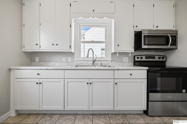 kitchen with appliances with stainless steel finishes, white cabinetry, and sink