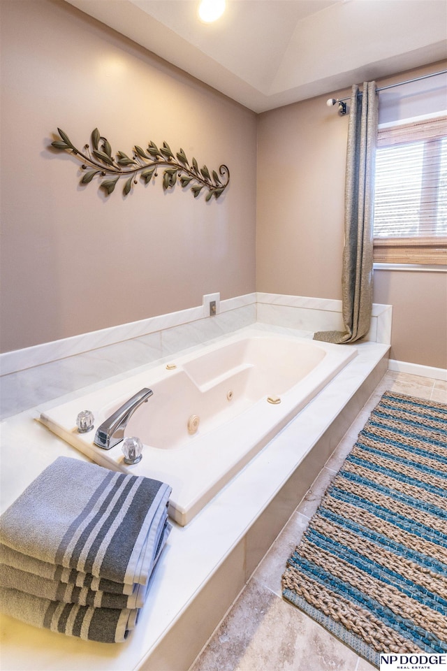 bathroom featuring tile patterned flooring, tiled tub, and vaulted ceiling