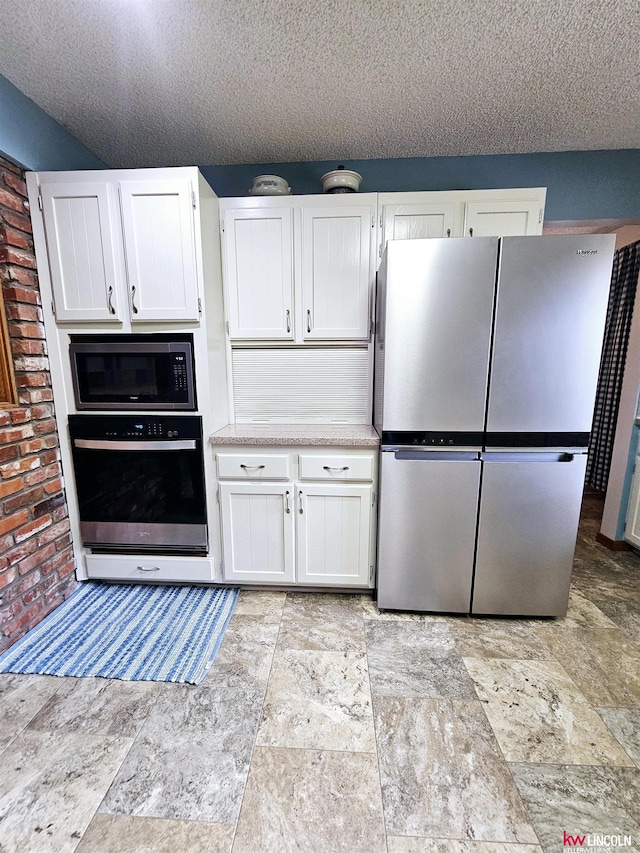 kitchen featuring a textured ceiling, built in microwave, white cabinetry, oven, and stainless steel refrigerator