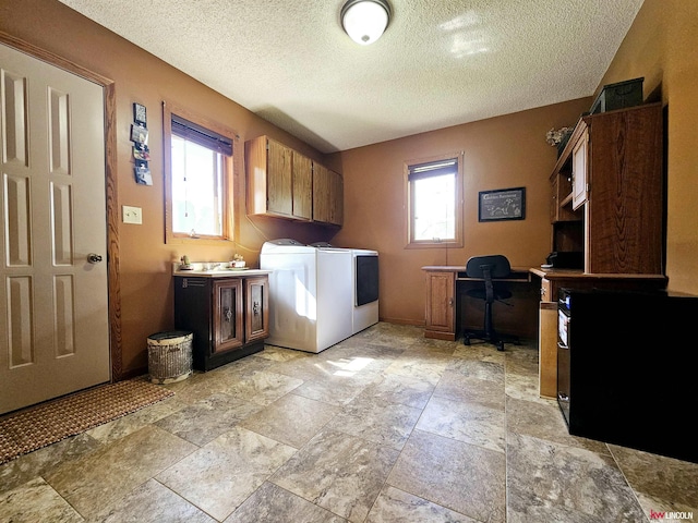 clothes washing area with cabinets, washer and clothes dryer, a healthy amount of sunlight, and a textured ceiling