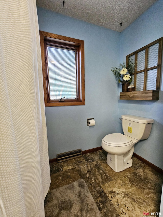 bathroom with toilet and a textured ceiling