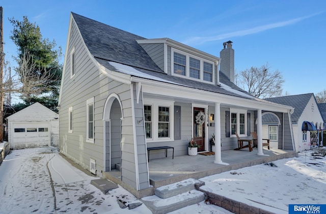 view of front of home featuring covered porch, a garage, and an outbuilding