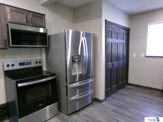 kitchen with appliances with stainless steel finishes, dark brown cabinetry, and light hardwood / wood-style flooring