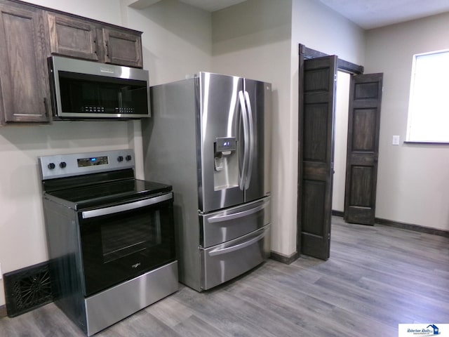 kitchen featuring appliances with stainless steel finishes, light hardwood / wood-style floors, and dark brown cabinets