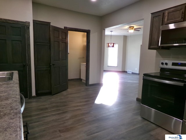 kitchen with pendant lighting, dark wood-type flooring, ceiling fan with notable chandelier, appliances with stainless steel finishes, and dark brown cabinets