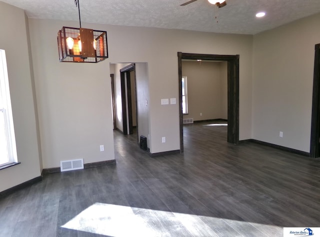 spare room featuring a textured ceiling, dark hardwood / wood-style floors, and ceiling fan with notable chandelier