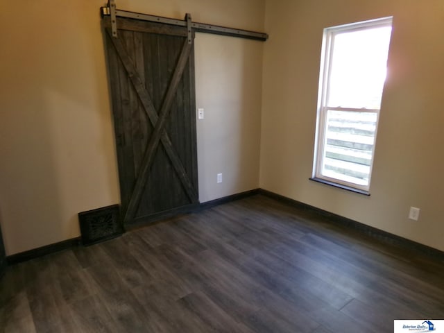 unfurnished room featuring dark hardwood / wood-style floors and a barn door