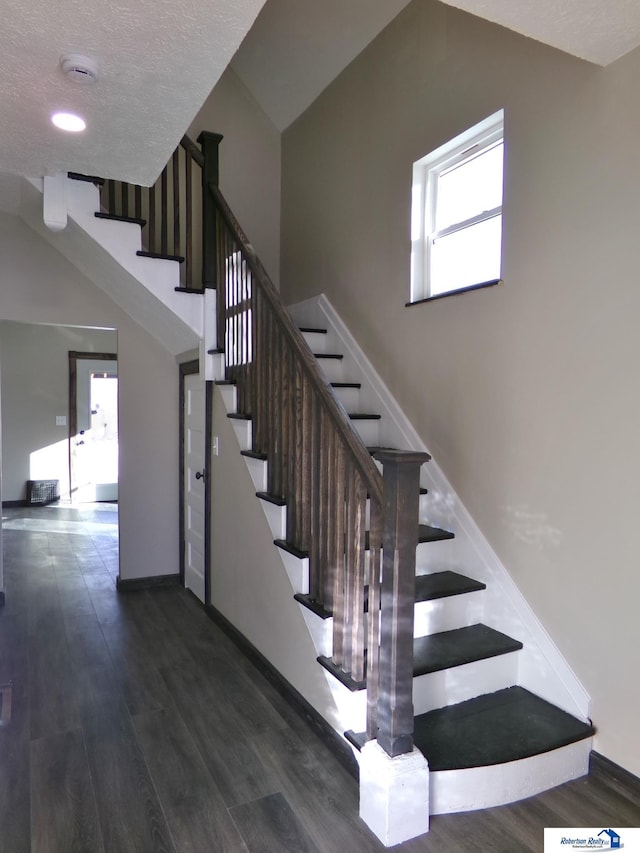 stairway with hardwood / wood-style flooring and a textured ceiling