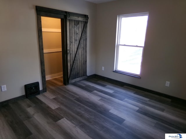 empty room with dark hardwood / wood-style floors and a barn door