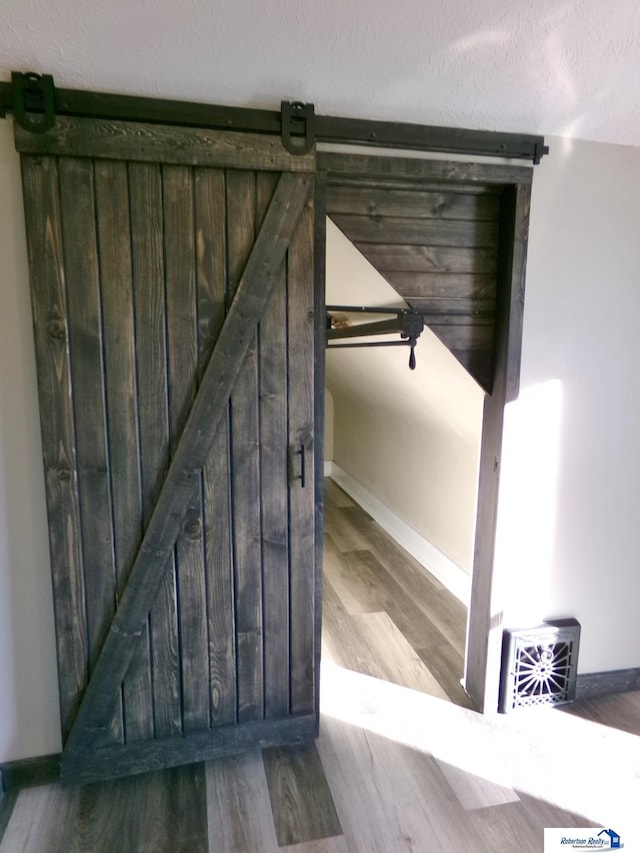 stairway featuring a barn door, hardwood / wood-style floors, and a textured ceiling