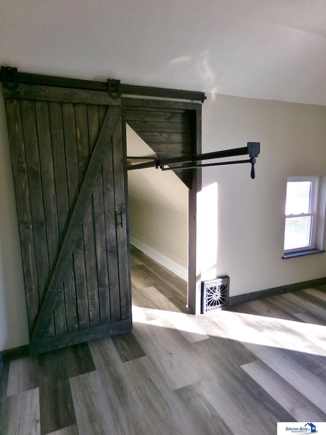 stairs with hardwood / wood-style flooring, a barn door, and a textured ceiling