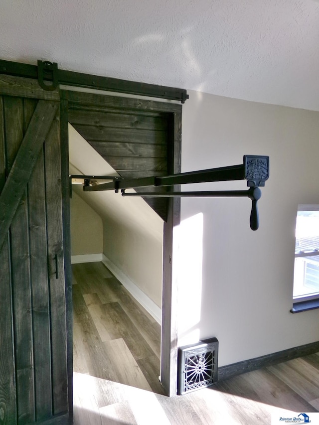 room details with a barn door, a textured ceiling, and hardwood / wood-style flooring