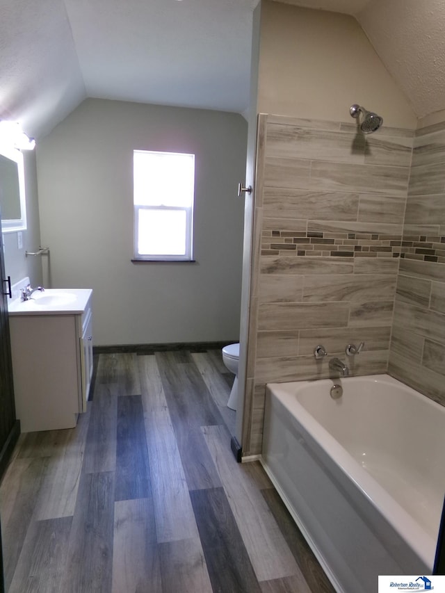 full bathroom featuring hardwood / wood-style floors, vanity, lofted ceiling, toilet, and tub / shower combination