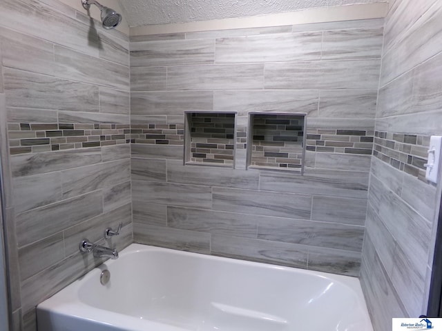 bathroom with tiled shower / bath combo and a textured ceiling